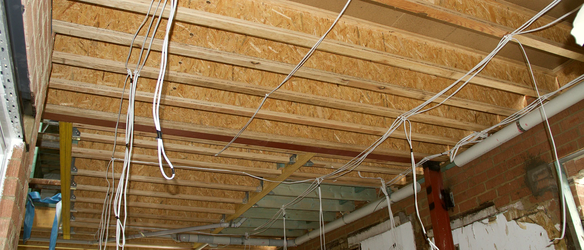 A residential roof cavity during rough-in, with new cabling run between the rafters.